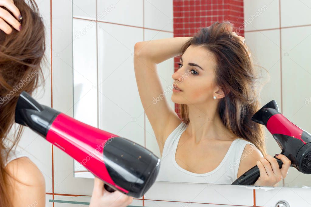 beautiful woman in bathroom dries hair