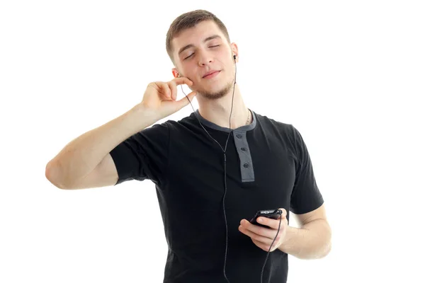De jonge man sloot zijn ogen en luistert naar muziek met hoofdtelefoon met de telefoon — Stockfoto