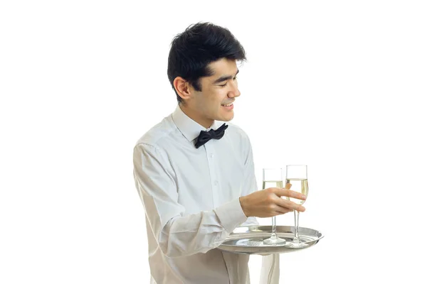 Garçom adorável sorrindo leva um copo de vinho com uma bandeja — Fotografia de Stock