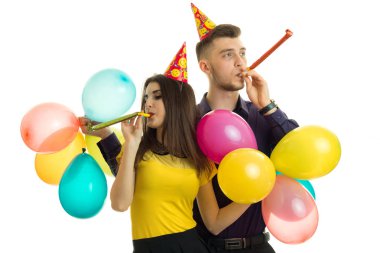 mutlu genç çift ellerinde balonlar ile bir doğum günü partisinde boynuz üfleme