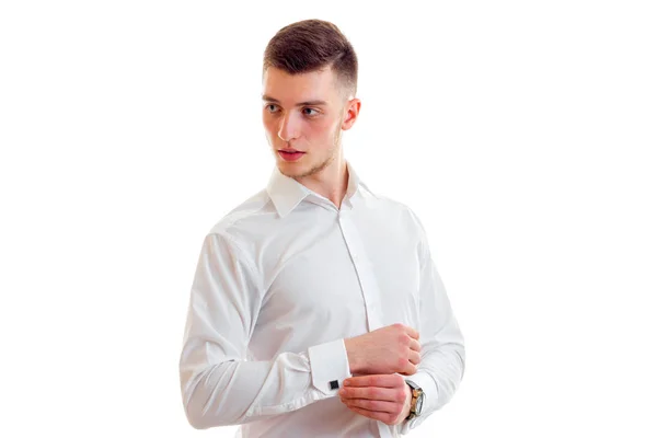 A stylish young man in a white shirt looks away and adjust by sleeve — Stock Photo, Image