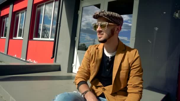 Charming guy in fashionable clothes and mirrored glasses sitting and drink coffee — Stock Video