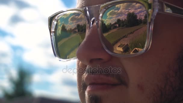 Man met baard staat te midden van de wolken in heldere gespiegelde glazen — Stockvideo