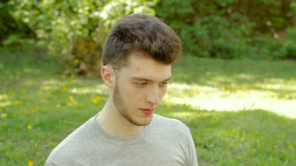 Gondolkodó fiatal srác eszik egy tölcsér fagylaltot a parkban — Stock videók