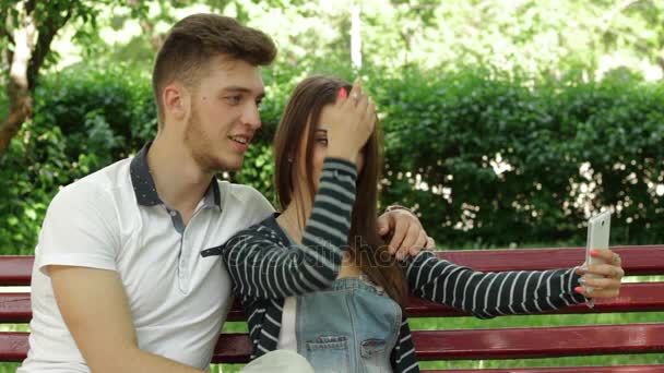 Pareja amorosa hacer selfi en el parque en un banco — Vídeo de stock