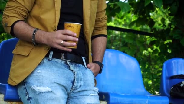 Toller Typ mit Brille und Hut steht im Park und trinkt Kaffee — Stockvideo