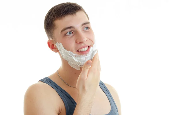 Cheerful young man with foam on dace smiling and looking away — Stock Photo, Image