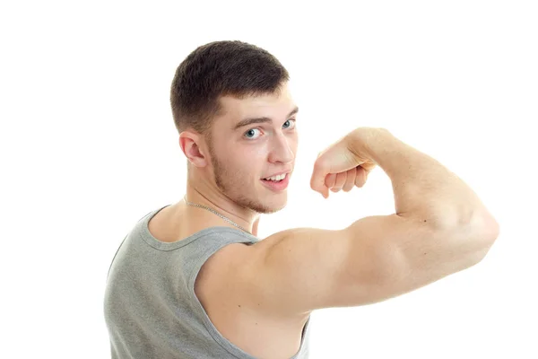 Mladý sportovní muže, ukazující jeho biceps a při pohledu na fotoaparát — Stock fotografie