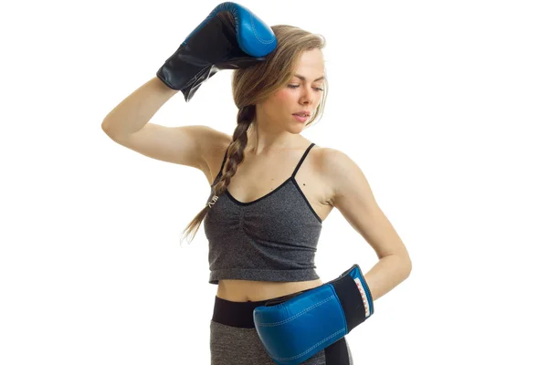 Jeune femme blonde mignonne dans une salle d'uniforme de sport avec des gants de boxe bleus — Photo