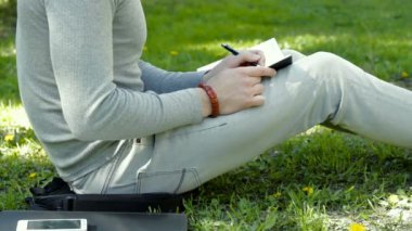 içinde defter Park ve geçici girdilerindeki çimlerde oturan adam