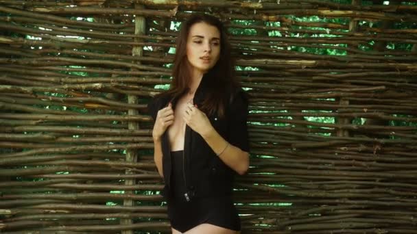Sensuell ung brunett dam i provocerande kläder står vid staketet och tittar åt sidan — Stockvideo