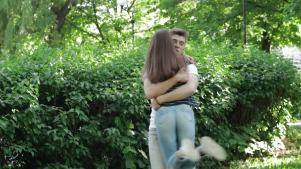 Kerl umarmt und wirbelt in ihren Armen hübsches Mädchen im Park — Stockvideo