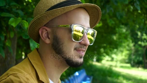 Jovem homem bonito em chapéu e óculos de sol sorrindo ao ar livre — Vídeo de Stock