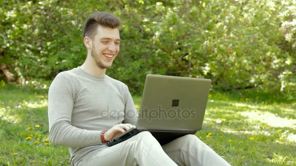 Glad ung pojke skrattar och arbetar med laptop — Stockvideo