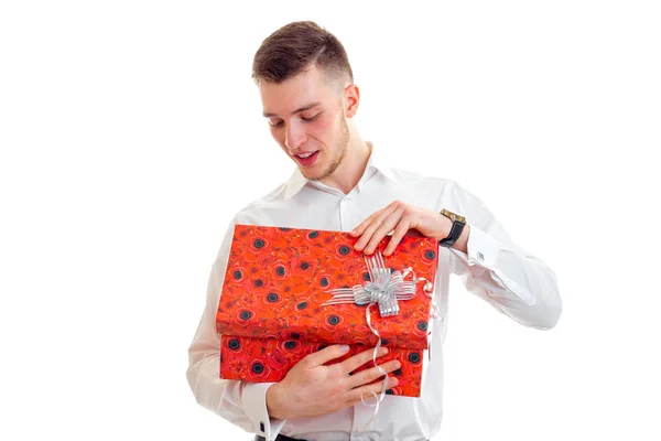 Handsome young guy opens the gift in red box — Stock Photo, Image