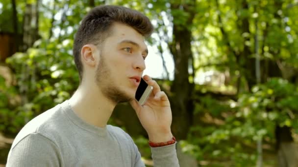 Веселий молодий гей розмовляє по телефону на відкритому повітрі і сміється — стокове відео