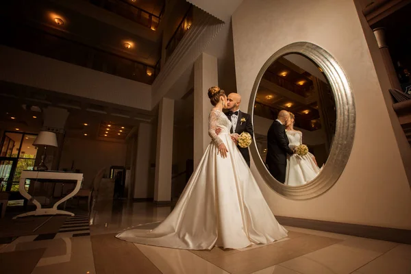 Schöne blonde Braut mit Bräutigam am Spiegel — Stockfoto