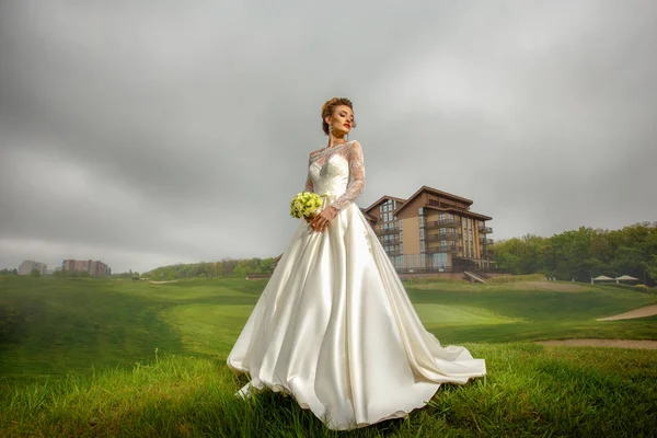 Hinreißende blonde Braut im Hochzeitsanzug und Blumenstrauß in ihren Händen — Stockfoto