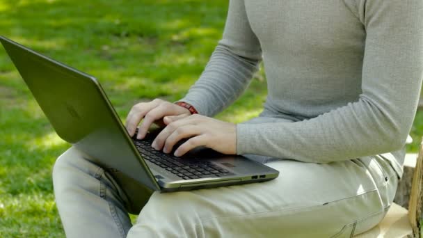 Närbild av ung kille arbetar med laptop utomhus — Stockvideo
