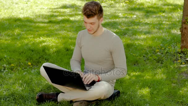 Trött man som arbetar med laptop i parken och än går bort — Stockvideo