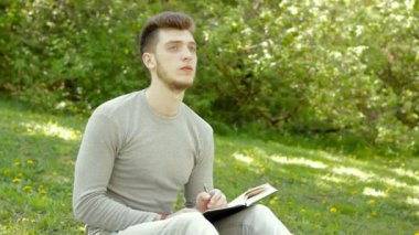 Genç düşünceli öğrenci olun notlar bir çim üzerinde oturur