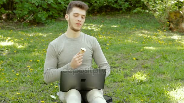 Šťastný mladý muž občerstvení a zmrzlina kornout a směje se venku — Stock video