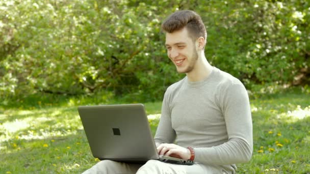 Vrolijke jongeman freelancer werken met laptop buiten — Stockvideo