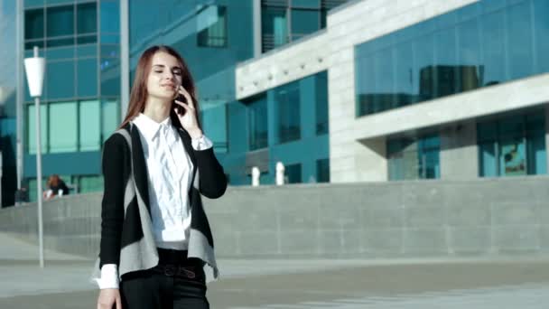 Beautiful young brunette calling near business center — Stock Video