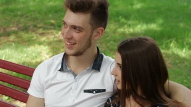 Genç çift sarılma ve bir bankta konuşuyor