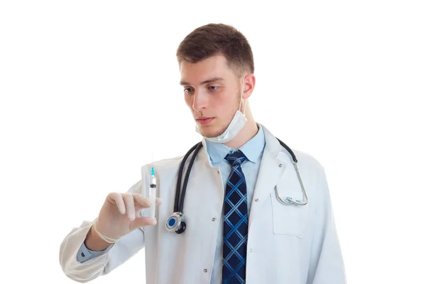 Bir doktor önlük ve beyaz bir arka plan üzerinde izole bir aşı ile bir şırınga tutarak onun yüzünde maske — Stok fotoğraf