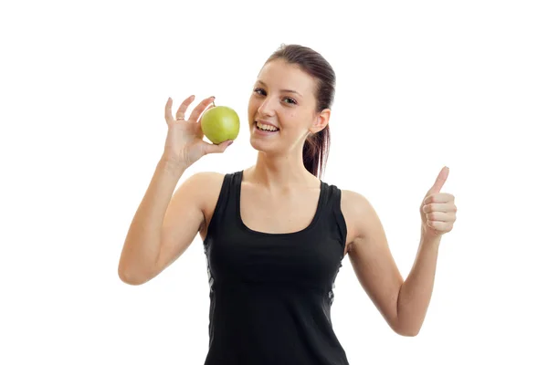 Horizontal portrait of young slim girl in a black t-shirt who holds in her hand a Green Apple and shows class — Stock Photo, Image