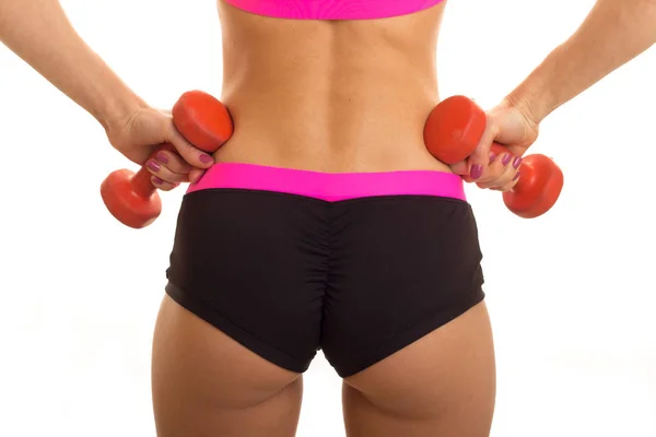 A close-up portrait of female sexual buttocks in sports shorts and with dumbbells in your hands — Stock Photo, Image