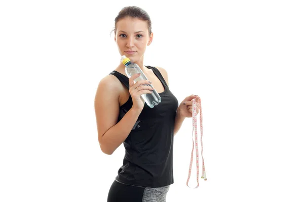 Mladí fitness dívka stojí ve studiu a vyměřuji a láhev vody — Stock fotografie