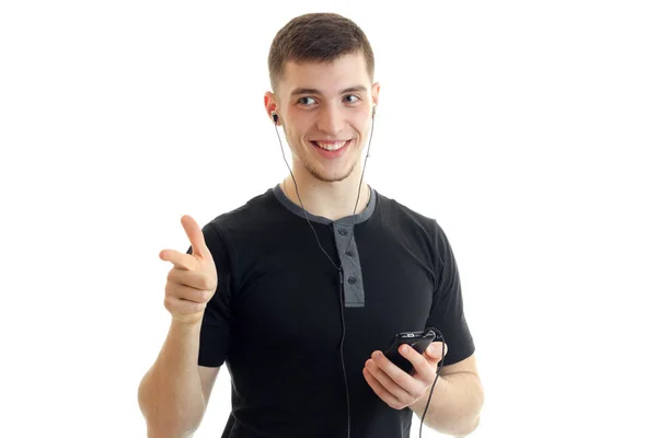 Encantador y encantador joven sosteniendo un teléfono y posando para la cámara — Foto de Stock