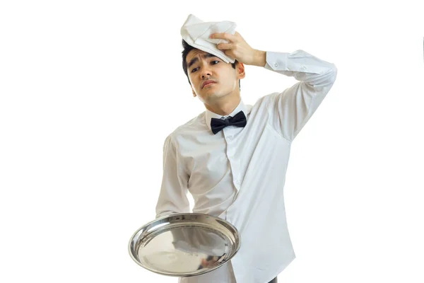 El joven camarero cansado sostiene una bandeja y le pone una servilleta en la cabeza — Foto de Stock