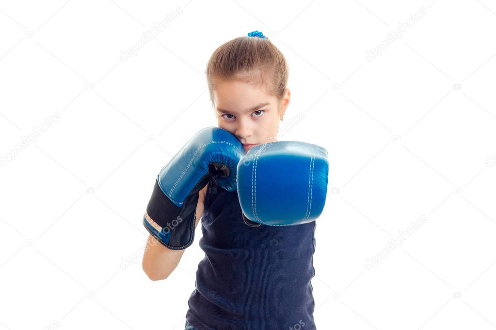 little serious girl with boxing gloves stands in front of the camera and pulls the hands