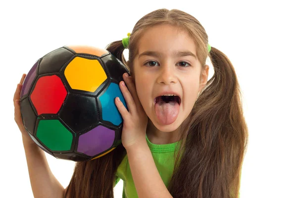 Porträt eines fröhlichen Mädchens mit einem Fußball zeigt Zunge — Stockfoto