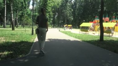 Genç sarışın Bayan parkta yüksek topuklar üzerinde yürür.