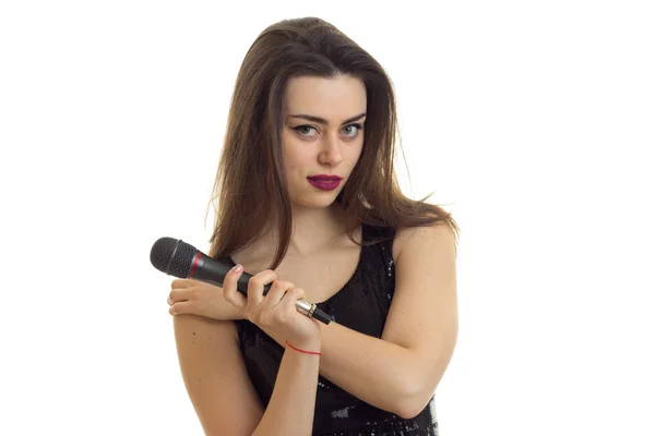Schöne brünette Mädchen mit Mikrofon in den Händen blickt in die Kamera — Stockfoto