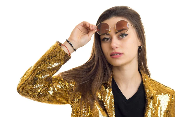 Primer plano retrato de mujer morena bonita en gafas de sol redondas y chaqueta dorada mirando a la cámara —  Fotos de Stock