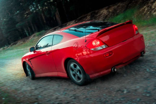 Красный спортивный автомобиль движется по пересеченной местности — стоковое фото