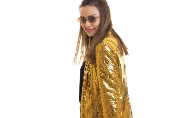 Красивая девушка в круглых солнцезащитных очках и золотой куртке улыбается на камеру — стоковое фото