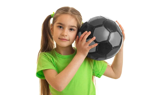 Schönes kleines Mädchen mit grauem Fußball in der Hand blickt in die Kamera — Stockfoto