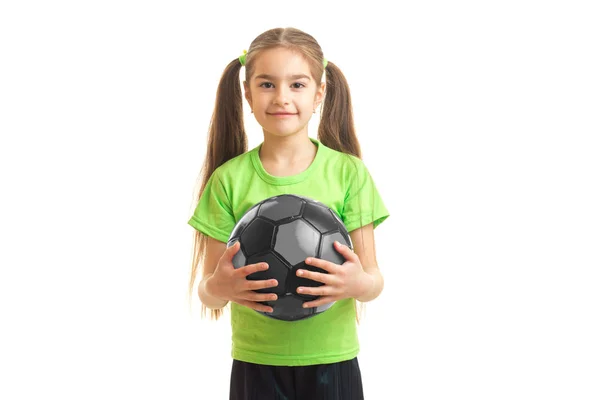 Nettes kleines Mädchen in grünem Hemd, das einen Fußball in den Händen hält — Stockfoto