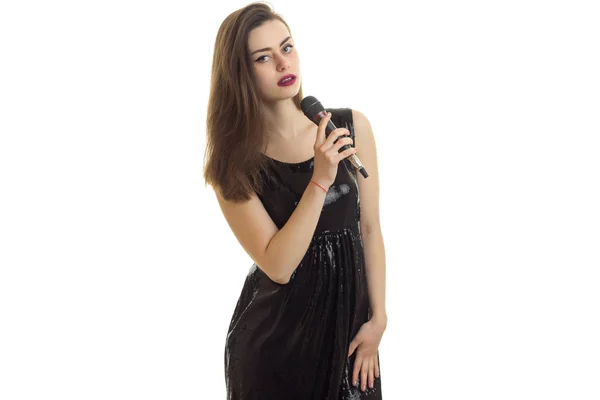 Belle jeune fille en robe noire tenant un microphone — Photo