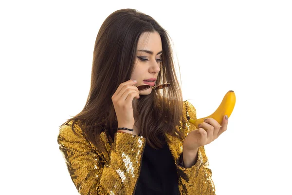 Портрет красивой девушки в яркой куртке в очках и с бананом в руке на белом фоне — стоковое фото