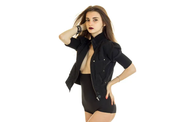 Сексуальная брюнетка в черных шортах и куртка с обнаженной грудью стоит перед камерой и держит руку сбоку. — стоковое фото
