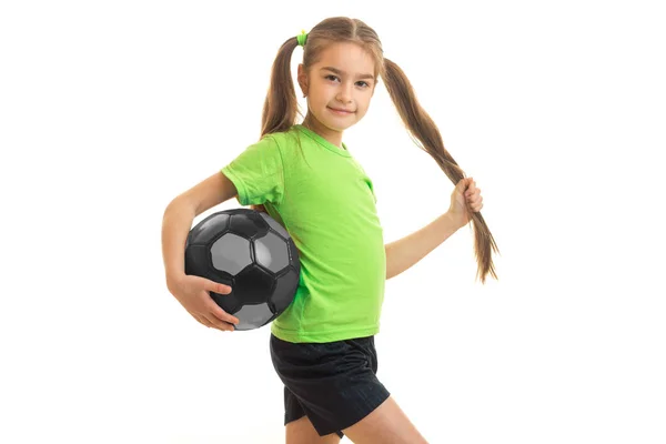 可爱的小女孩穿着绿色衬衫与足球球在手中 — 图库照片