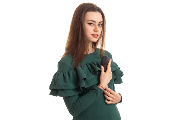 Молода брюнетка в зеленій сукні з мікрофоном в руках — стокове фото