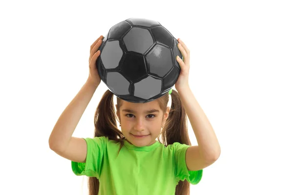 Hübsches kleines Mädchen im grünen Hemd mit Fußballball in der Hand — Stockfoto